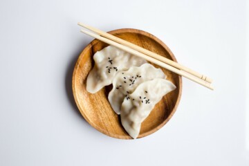 White dumplings on a bamboo plate, with chopsticks on the side