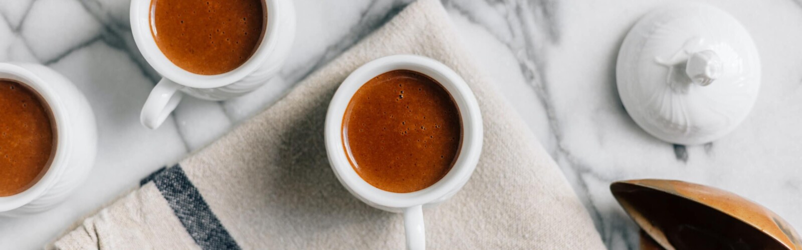 Cups of coffee in white mugs on a marble kitchen counter