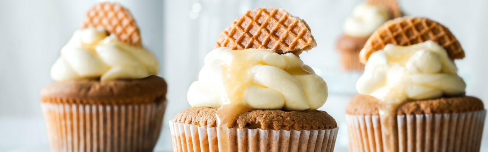 Image includes three cupcakes, all with yellow frosting and a cookie in the frosting for decoration.