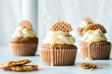 Image includes three cupcakes, all with yellow frosting and a cookie in the frosting for decoration.