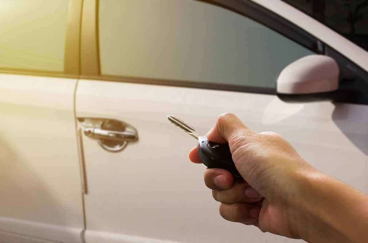 hand holds key pointed towards new car door.