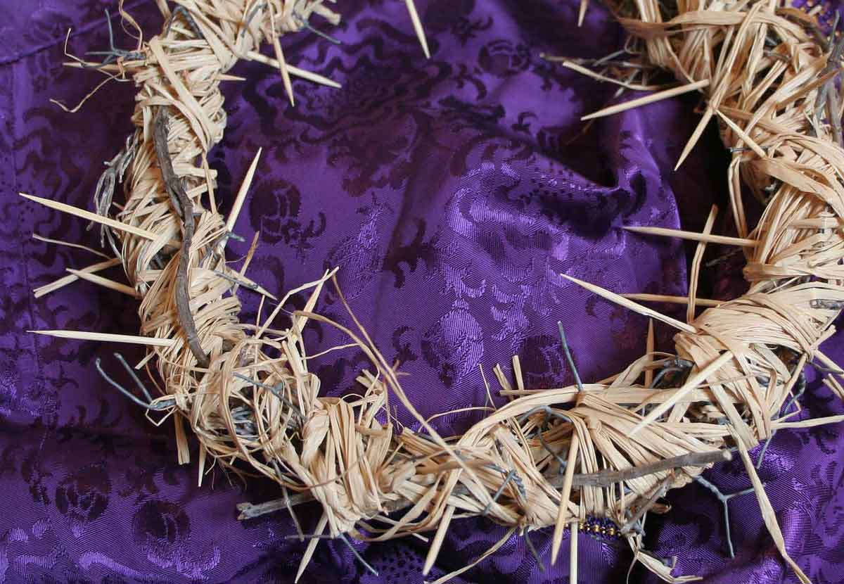 straw crown on purple satin represenrs the crown of thorn to christians.