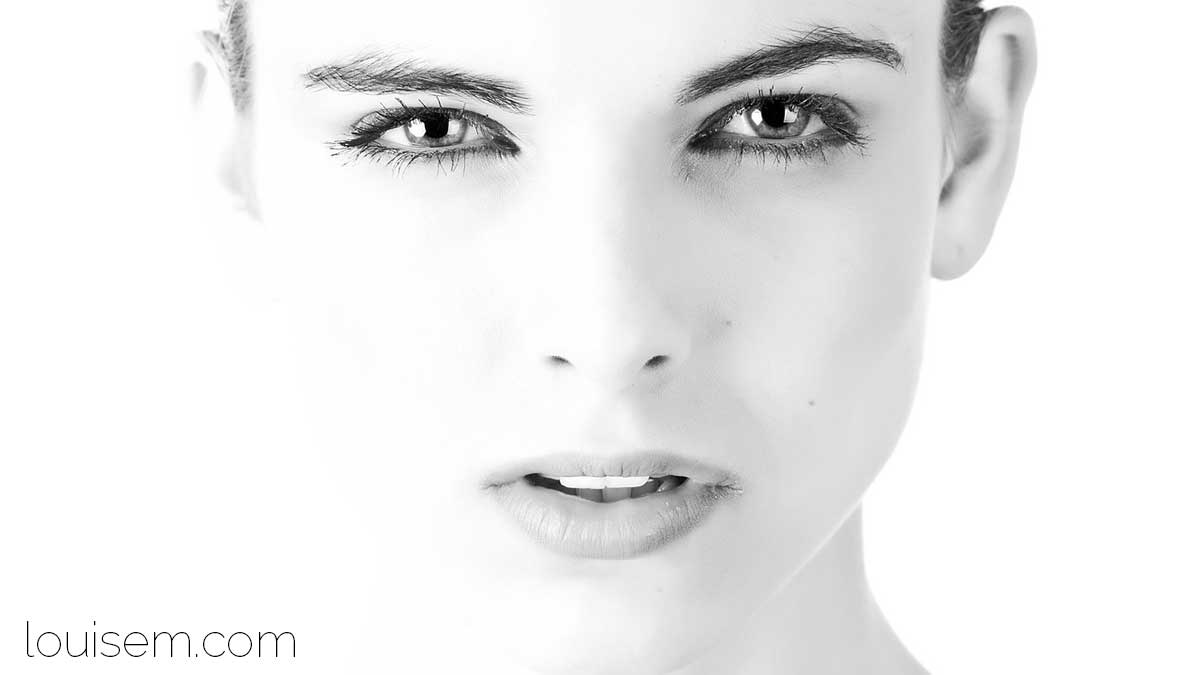 closeup of woman's face in bright white room squinting at all the light.