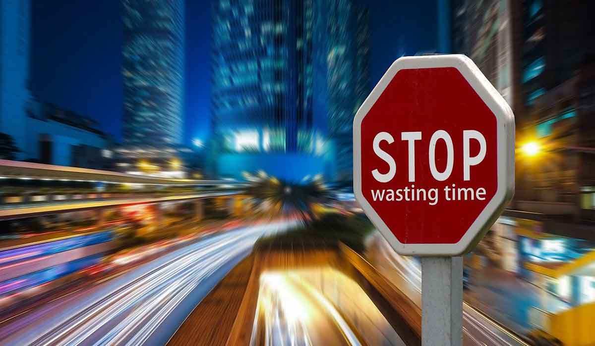 streaks of traffic lights with red stop sign and blue buildings at night.