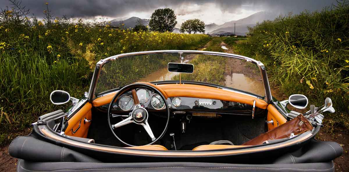 vintage auto on one lane road through flower field.